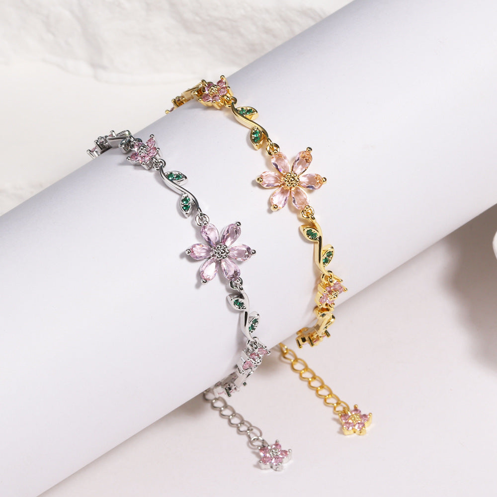 Three floral bracelets in gold, silver, and pink on a white surface