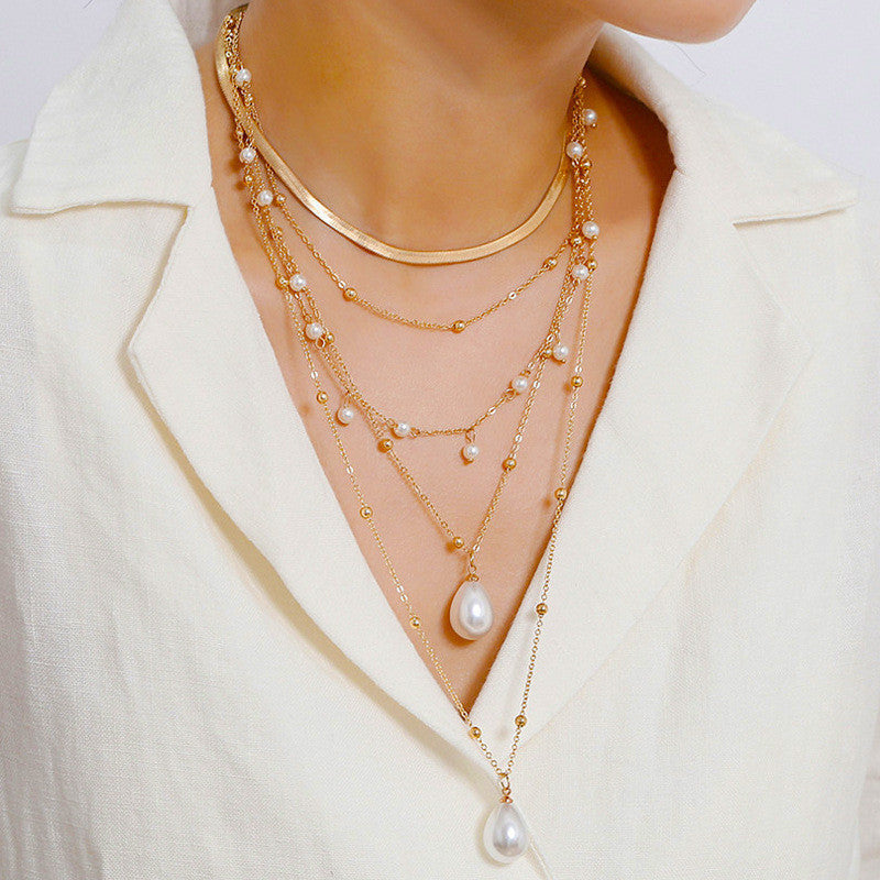 Gold necklace with pearls worn by a person in a white outfit