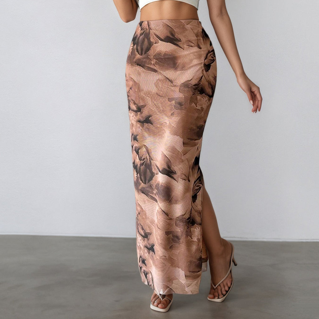 Woman wearing a white crop top and a long, patterned skirt against a plain background