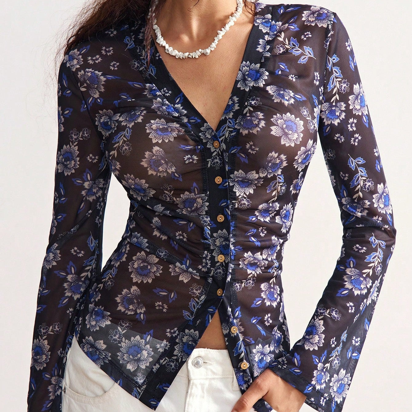 Woman wearing a dark floral blouse with long sleeves on a white background